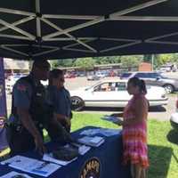 <p>Ramapo police officers discuss the upcoming police exam with a member of the public Saturday in Spring Valley.</p>