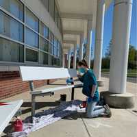 <p>A student paints a bench to show school spirit at Saxe Middle School.</p>