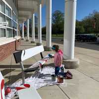 <p>A student paints a bench to show school spirit at Saxe Middle School.</p>