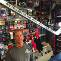 <p>Doug Mathews, owner of WESCO Sports Center, stands behind an award for being the best hockey retailer in the country as awarded by Bauer, a hockey equipment company.</p>