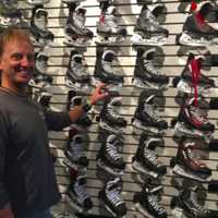 <p>Doug Mathews stands by a wall of skates at the WESCO Sports Center.</p>