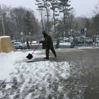 <p>A man at work cleaning snow and slush from Greenwich Library front entrance.</p>