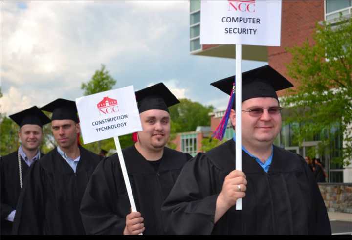 Norwalk Community College graduates display signs with the names of the degrees they received.