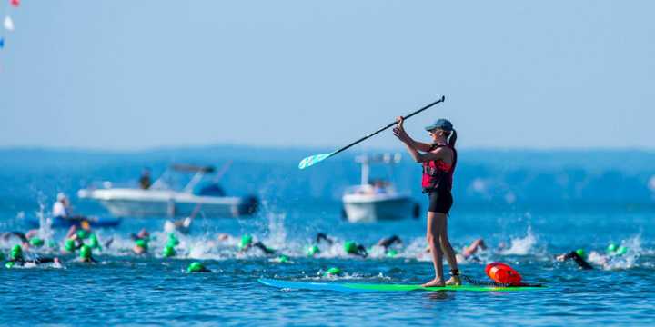 A woman on a paddleboard keeps an eye on the swimmers near the start of the event.