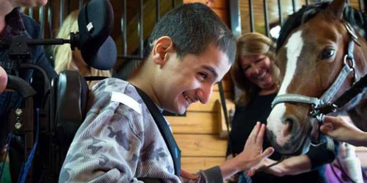 A young boy with special needs pets a horse at Pony Power in Mahwah.