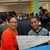 <p>Qadir Emile-Weekes, a ninth-grader from Saunders High School, shows off his &quot;vision&quot; banner while mom, Lorraine, and younger brother look on. The banners detail the students&#x27; goals for high school and college.</p>