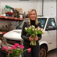 <p>Christina Foley holding tulips, with the delivery van is in the background. It is kept inside the shop.</p>