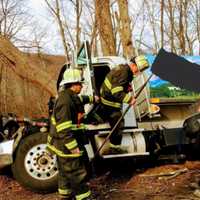 <p>Members of the Stepney Fire Department in Monroe work Monday to clean up an oil spill after an oil truck left the roadway on Judd Road at the Easton border.</p>