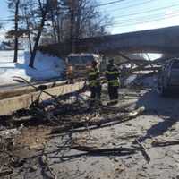 <p>Debris from a fallen tree covers a car and blocks the southbound side of the Merritt Parkway in Greenwich on Monday. Greenwich firefighters work to clear the scene.</p>