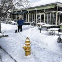 <p>An employee at Harborview Market keeps the sidewalk clear.</p>