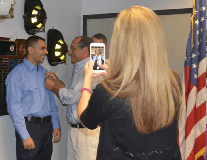 Andrew Ponteciello receives his badge from his father as a family member snaps a few photos.