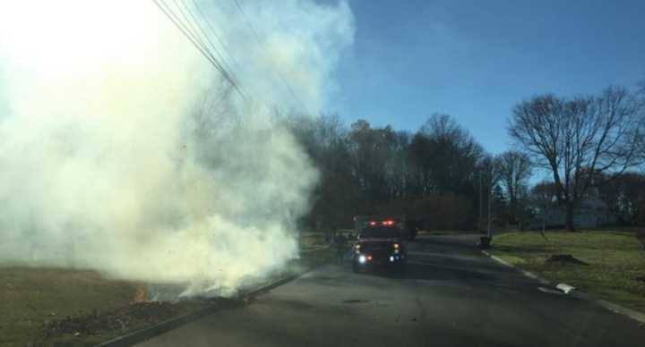 Firefighters from Long Hill Volunteer Fire Co. #1 douse a pile of burning leaves.