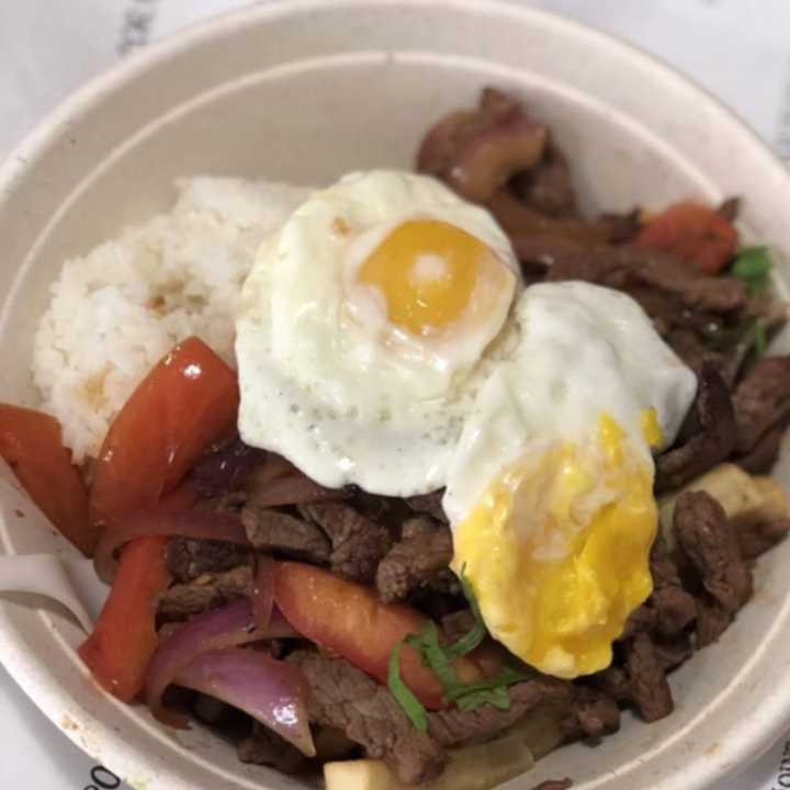 Lomo Saltado Moltado (Beef over rice and fries with tomatoes and fried egg) from Purple Corn Peruvian Rotisserie Joint, located at 72 Mamaroneck Avenue.