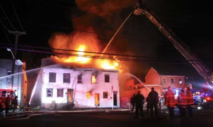 Firefighters battle a blaze that destroyed three attached row houses in Trenton overnight. One occupant died.