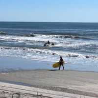 <p>Zeke Orzech walking with his paddle board, right, and the swimmer on a fire department jet ski headed back to shore.</p>