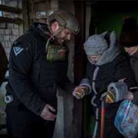 <p>Pete Reed helps an elderly woman evacuate in Ukraine.</p>