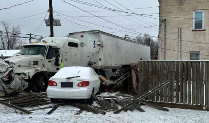 The tractor trailer struck several cars and a building, trapping an occupant inside, police said.