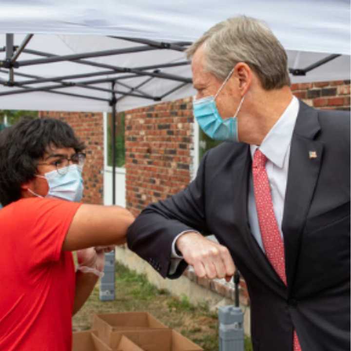 Gov. Charlie Baker exchanges a COVID-19-friendly elbow bump with a farmer&#x27;s market vendor.