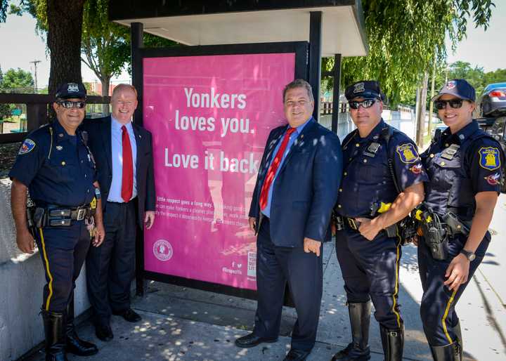 City Council President Liam McLaughlin, Mayor Mike Spano and local police officers show off one of the new anti-littering signs.