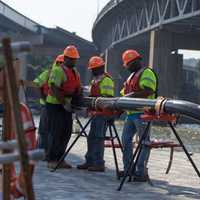 <p>Construction workers assemble conduits for the new Tappan Zee Bridge&#x27;s electrical system while standing on a temporary platform.</p>