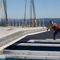 <p>Works continues on the new Tappan Zee Bridge. A worker is shown guiding the placement of a prefabricated road deck panel last week.</p>