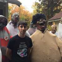 <p>Chris Arturi stands with the zombie wall at his haunted house, Thirty Knapp Road.</p>