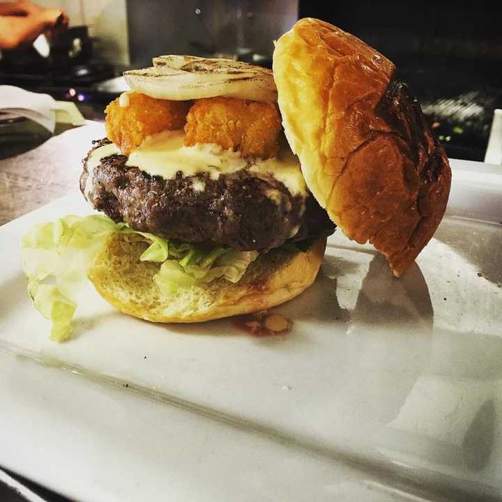 The Wisconsin Burger at Whistling Willie&#x27;s is topped with tater tots, grilled onions and cheese sauce.