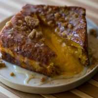 <p>Three layers of house-made bread, filled with salted duck egg yolk custard, fried in an egg batter, drizzled with condensed milk, topped with cookie crunchies. Filling oozes out as the french toast is cut open.</p>