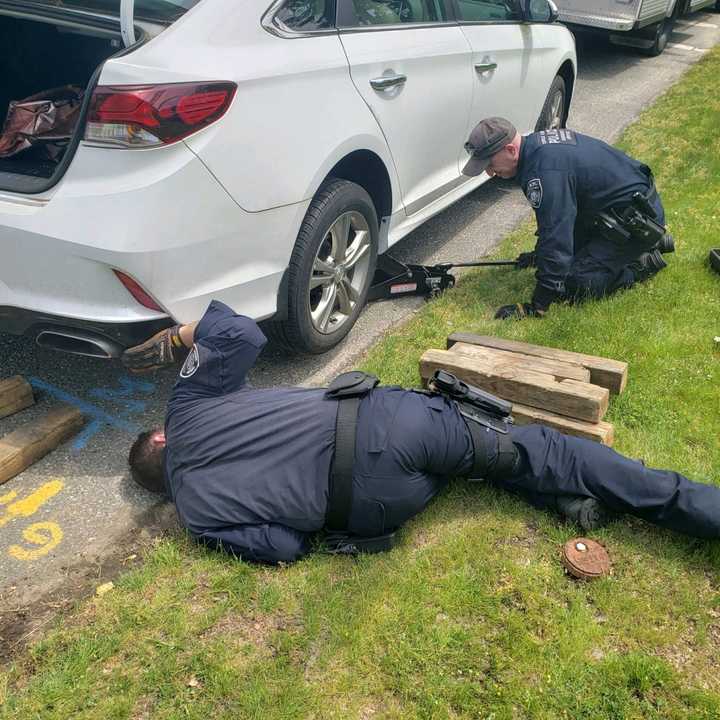 Suffolk County Police officers work to free a kitten stuck in a wheel well in North Babylon Thursday, June 2.