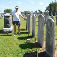 <p>Robert Neal Carpenter stands among a row of repaired headstones that had been knocked to the ground at the Wyckoff Reformed Church Cemetery.</p>