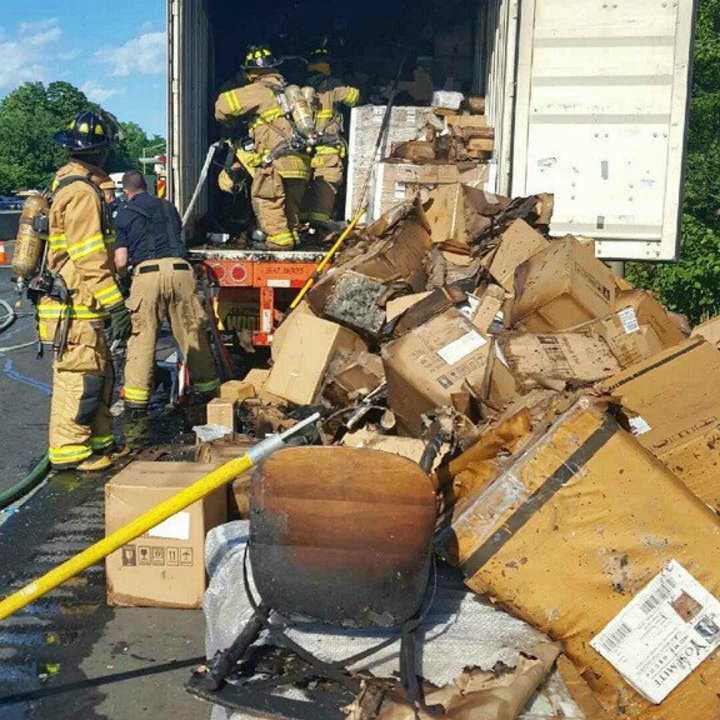 Firefighters empty the contents of a tractor-trailer after a fire Wednesday afternoon on I-95 in Stamford.