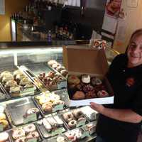 <p>Jule Hazou displays his freshly-made doughnuts in the New Milford store.</p>
