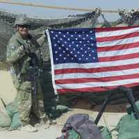 <p>Major Chris Carbone, left, holds the flag in Afghanistan on the 10th anniversary of 9/11.</p>