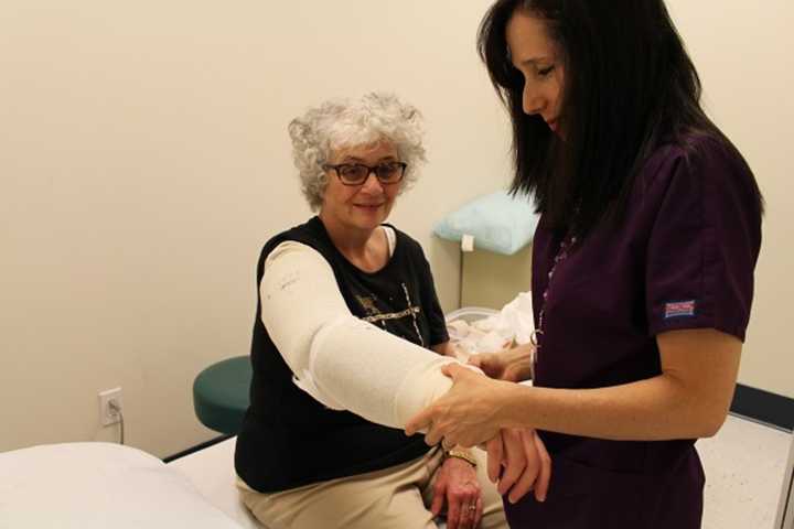 Elaine Young, pictured at lymphedema treatment session, gets her arm wrapped by therapist Lynette Lombardo.