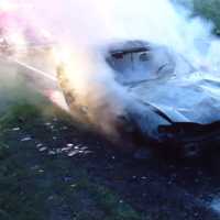 <p>Firefighters examine the smoking car Monday night on the Merritt Parkway. </p>