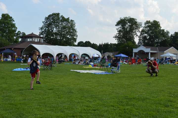 Somers&#x27; Darien Berisha throws to father Adam Berisha as families find their seats for fireworks at the Taste of Somers Food Festival Saturday night