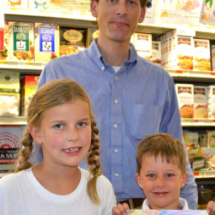 Alex Stewart, general manager of Walter Stewarts, back, stands with coloring contest winner Drew Burr, right, and Miller Burr, a coloring contest finalist.