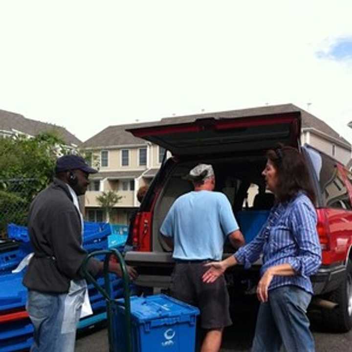 Volunteers with Community Plates make food deliveries in big blue bins. 