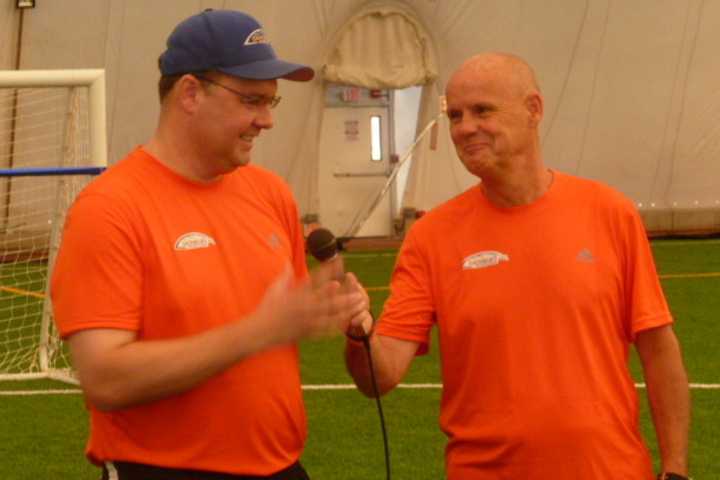 Ray Franklin, right, hands a microphone over to Kirk Bamford during a grand opening celebration Thursday at the Danbury Sports Dome. Both men are directors at the recently-opened facility.