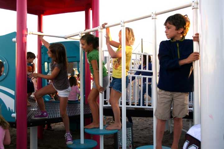 Children play on the new playground built in memory of Jessica Rekos on Fairfield&#x27;s Penfield Beach after its grand opening Saturday.