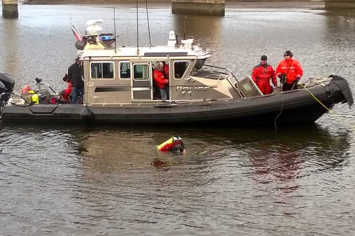 Based on information that the woman found dead in the Saugatuck River last week was likely hit by a train, divers search the water below the Saugatuck River railroad bridge in Westport on Tuesday afternoon for evidence.