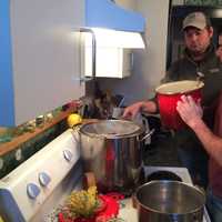 <p>John Wagner and Dan Latham begin the brewing process, straining and adding water to the oats after they have cooked. </p>