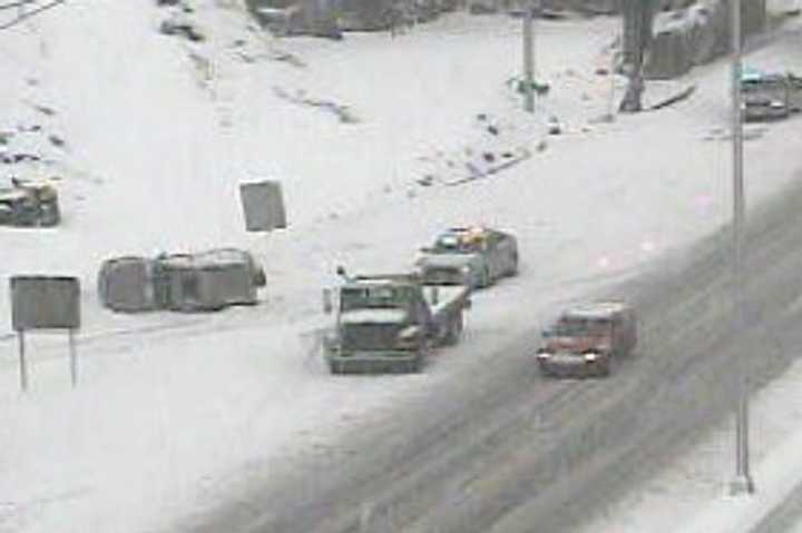 Police and a tow truck tend to a flipped car on I-95 near Exit 15 in Norwalk.