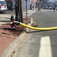 <p>Fire hoses stretch across the Post Road in Fairfield. </p>