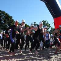 <p>Swimmers race from the starting area to enter the water.</p>