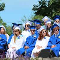 <p>During the ceremony, graduates listen to speakers. </p>