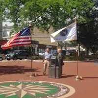 <p>Mayor Mark Bouhton and DPW Director Antonio Iadarola are flanked by flags at the ribbon-cutting for Kennedy Park. </p>