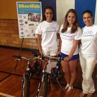 <p>Cristiana (left) and Lucia Villani (center) and their mother Adriane Defeo (right) help give away bikes to kids.</p>