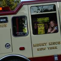 <p>A girl riding in a Mount Kisco firetruck waves.</p>