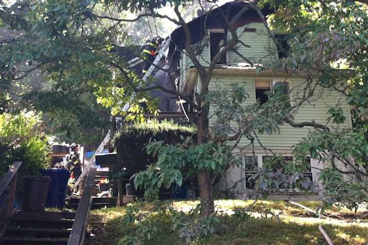 Norwalk firefighters put out the last smoldering remains of the house fire on Riverside Avenue on Thursday.